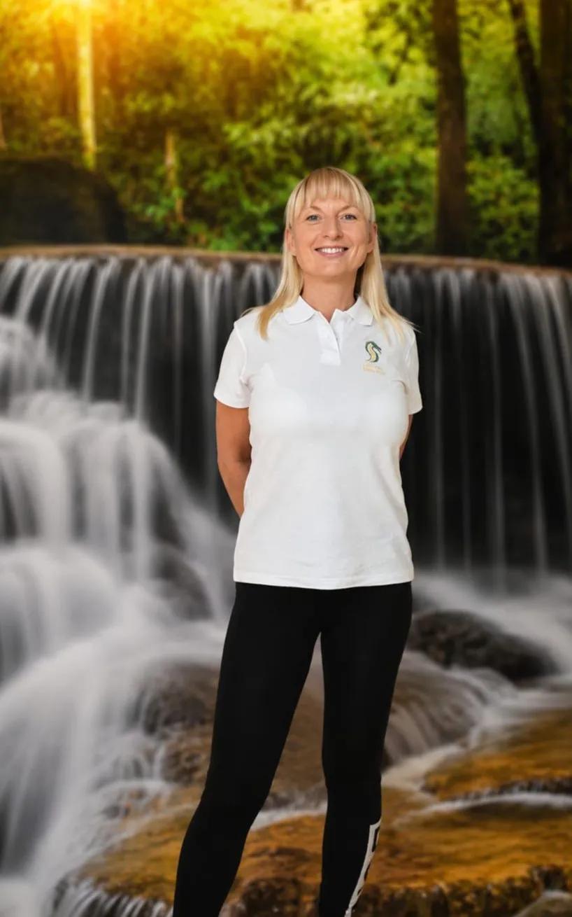 Katarzyna Sanicka-Müller im Praxis-Poloshirt vor dem Wasserfall-Motiv der Praxis
