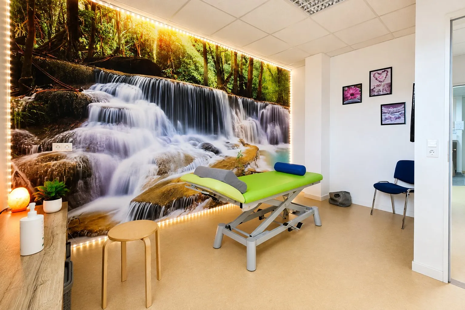 Behandlungsraum mit Therapieliege vor einem großformatigen Wasserfall-Motiv