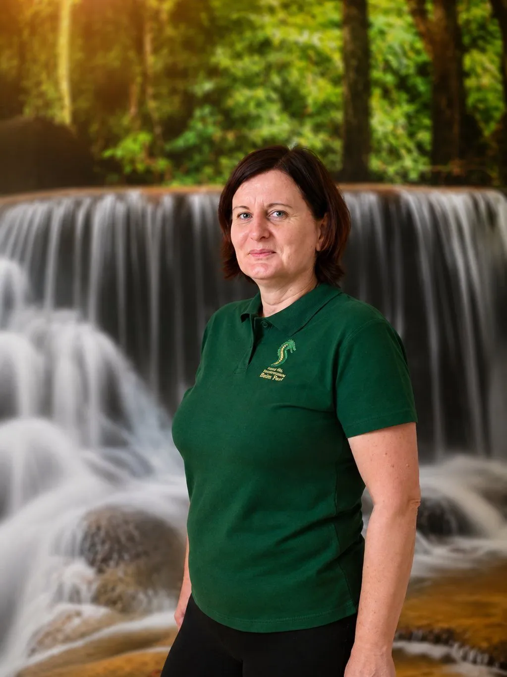 Bogusława Kubas im Praxis-Poloshirt vor dem Wasserfall-Motiv der Praxis